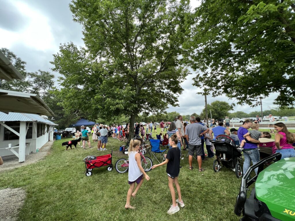 A crowd of adults and children gather on the fairgrounds.